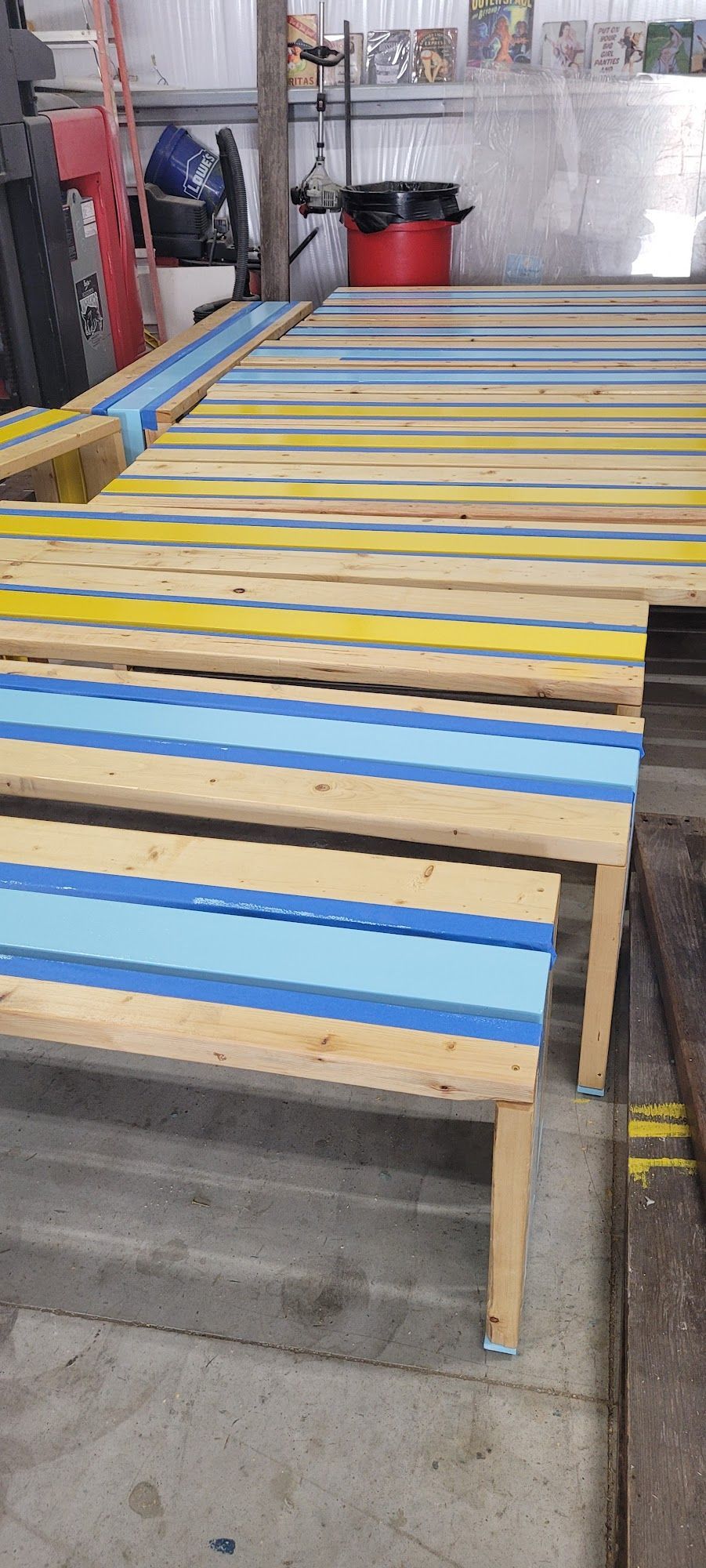 Wooden benches with blue and yellow stripes sit in an industrial setting.