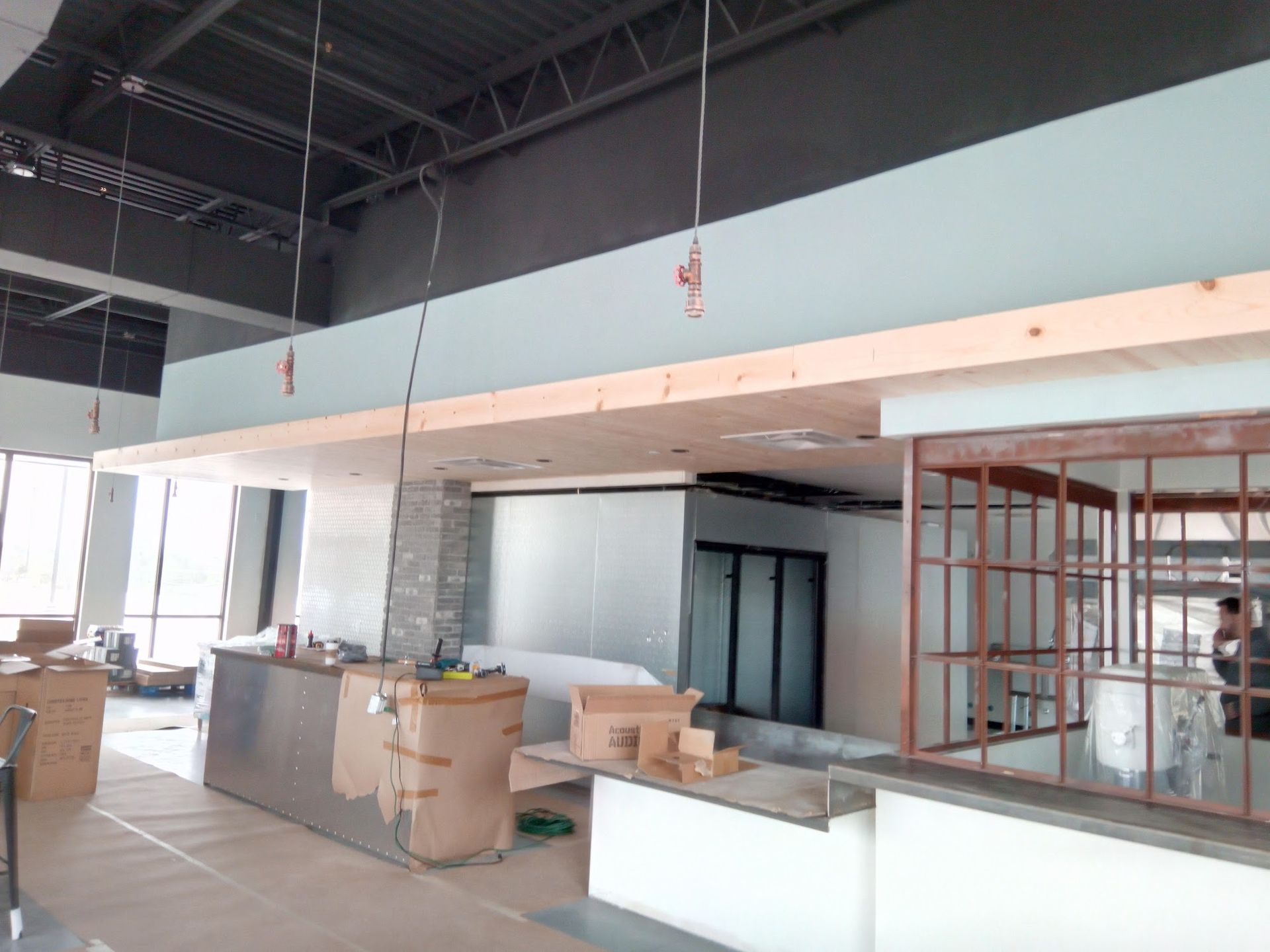 Interior construction scene; commercial space with unfinished bar, exposed beams, and light blue walls.