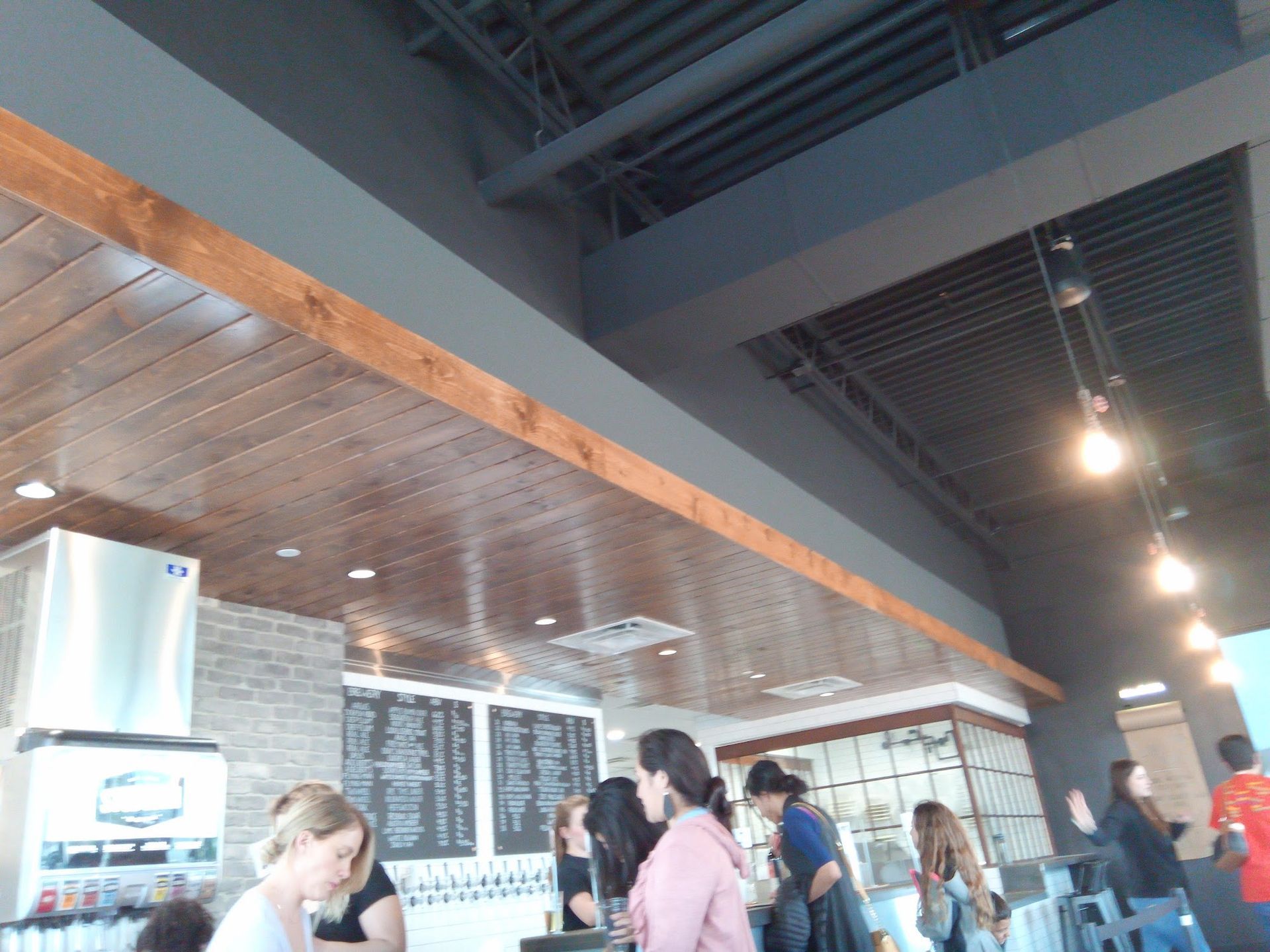 Interior of a cafe with people at the counter, wood and gray ceiling.