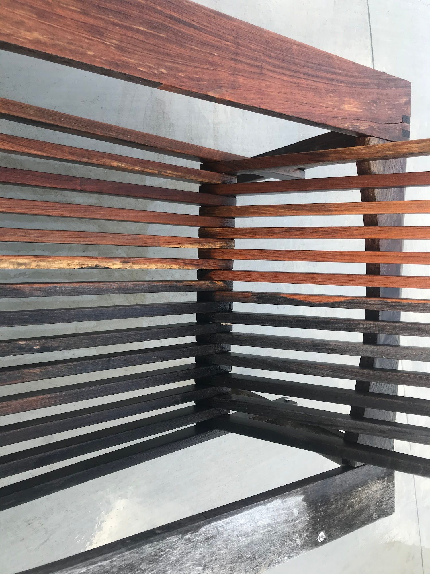 Wooden bench with dark brown frame and horizontal slats of varying colors.