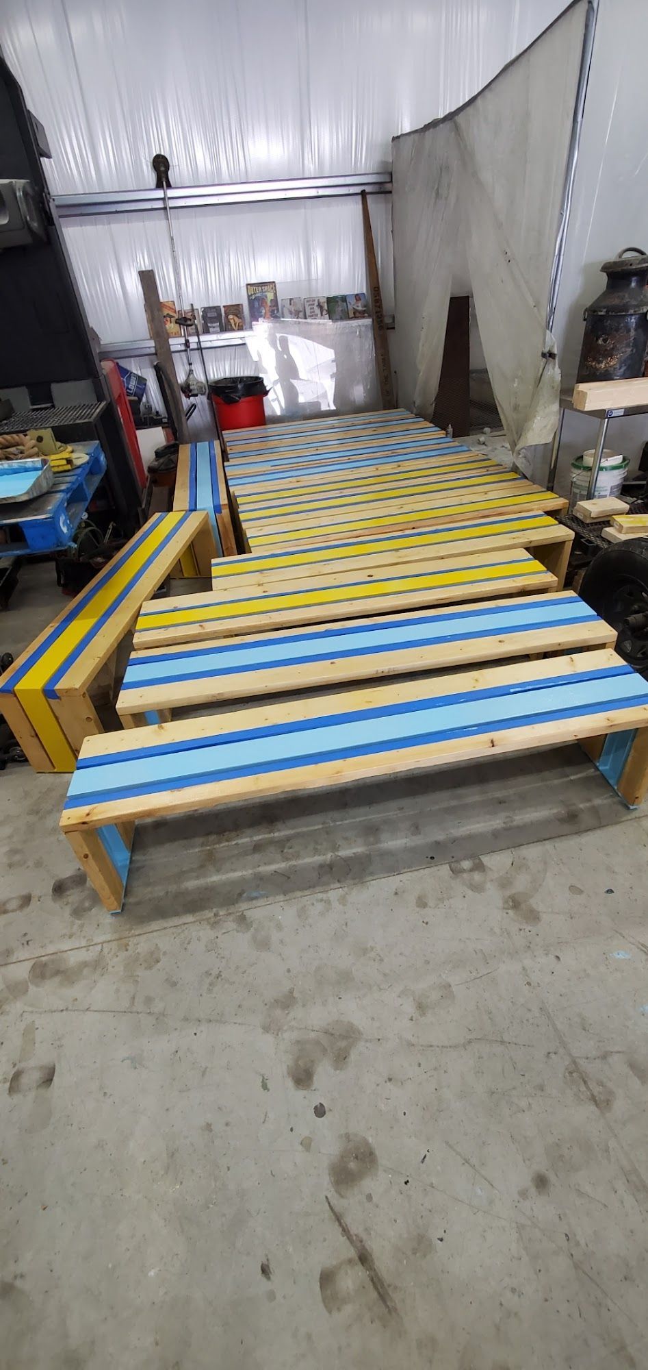 Wooden benches with blue and yellow paint in an industrial setting.