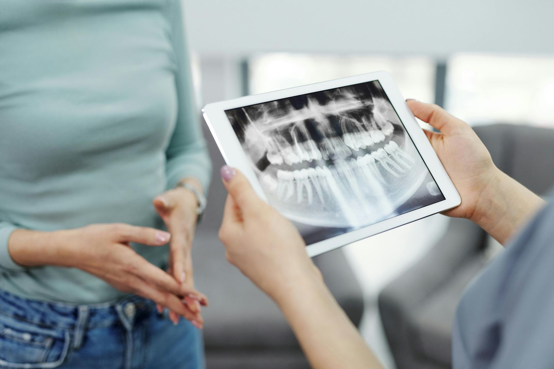 Dentist showing patient dental x-ray on tablet. Inside a dental office.