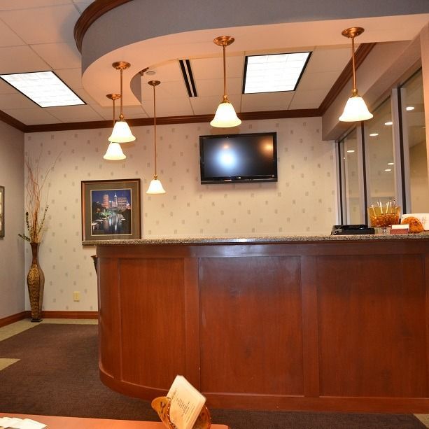 Reception area with wooden counter, pendant lights, TV, and waiting area.
