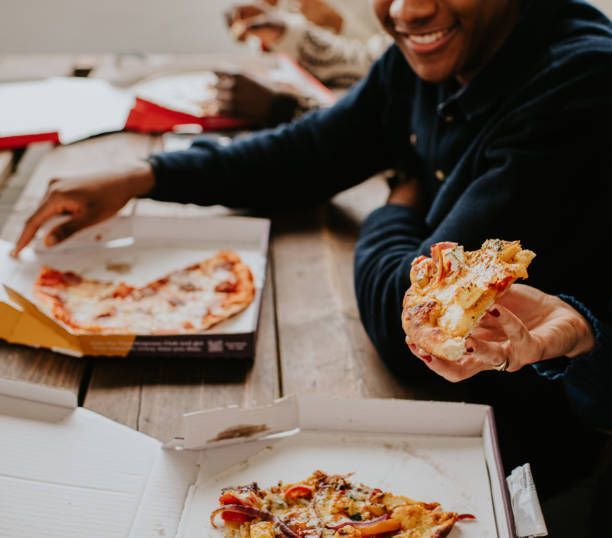 Close-up of hands holding freshly delivered pizza.