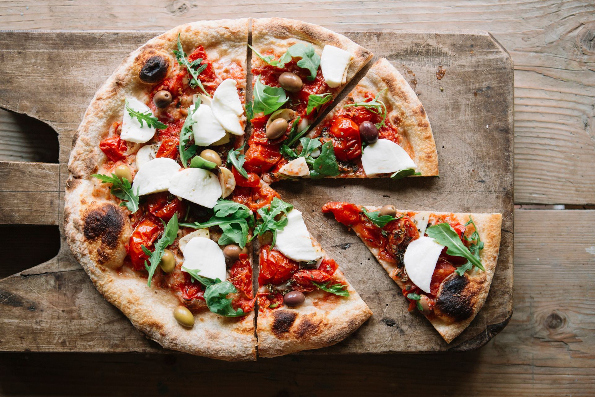 Sliced pizza on chopping board, overhead view