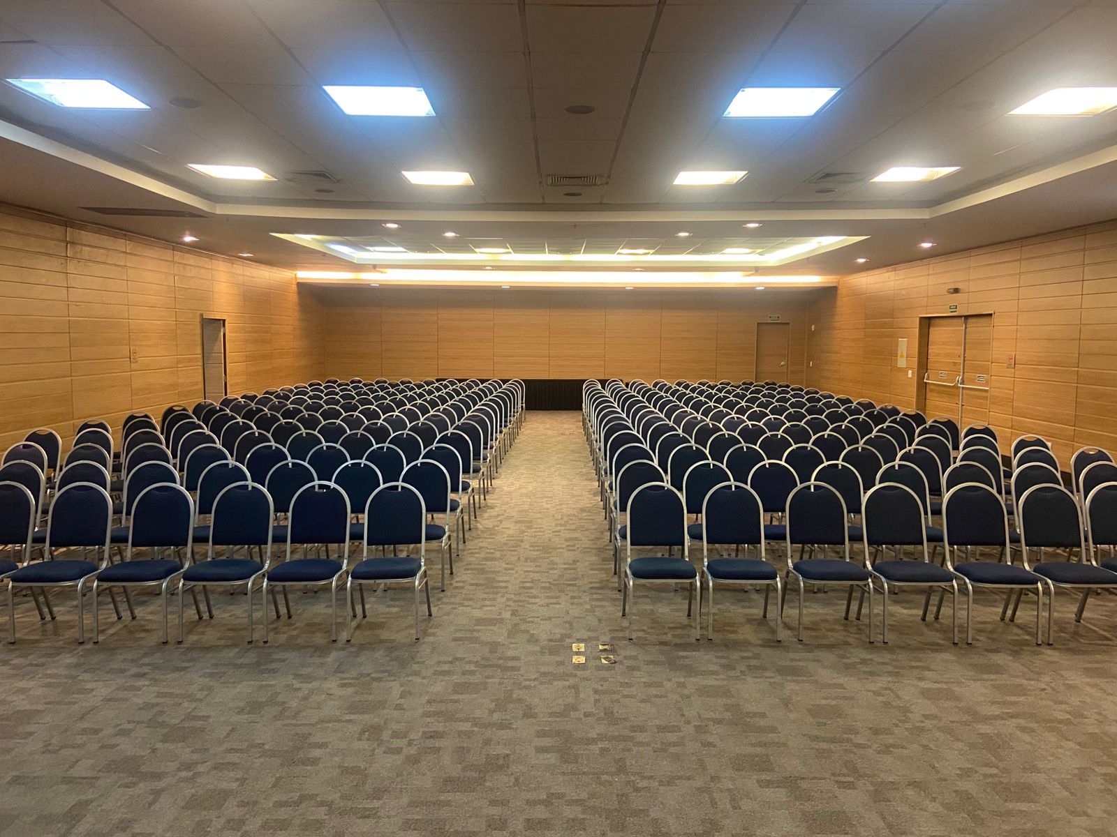 Uma grande sala de conferências cheia de fileiras de cadeiras azuis.