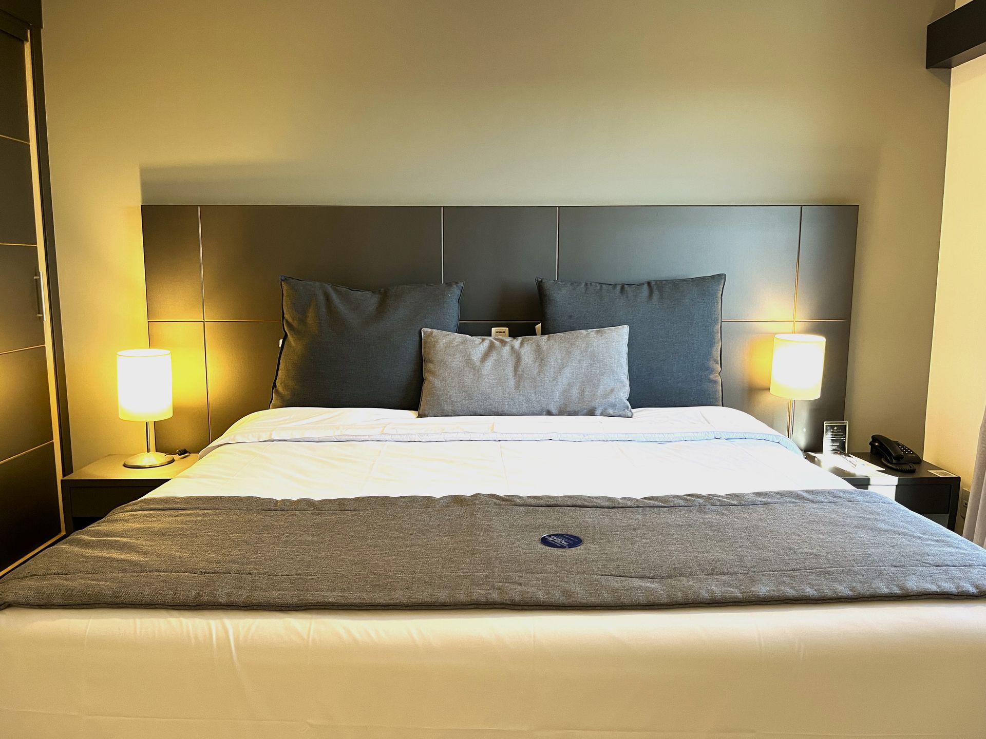 Uma cama king size com almofadas e abajures laterais.