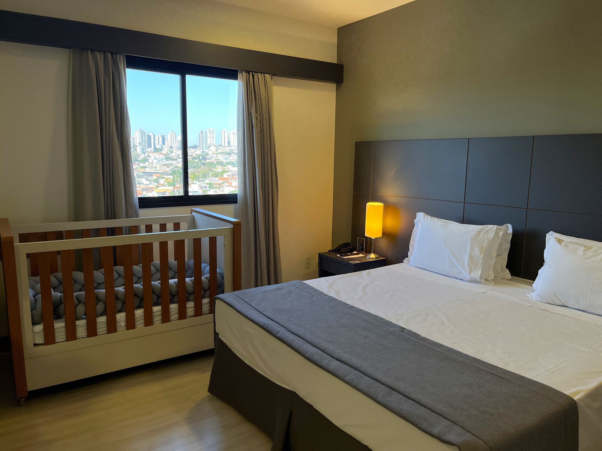 Um quarto de Hotel com uma cama king size e um berço.