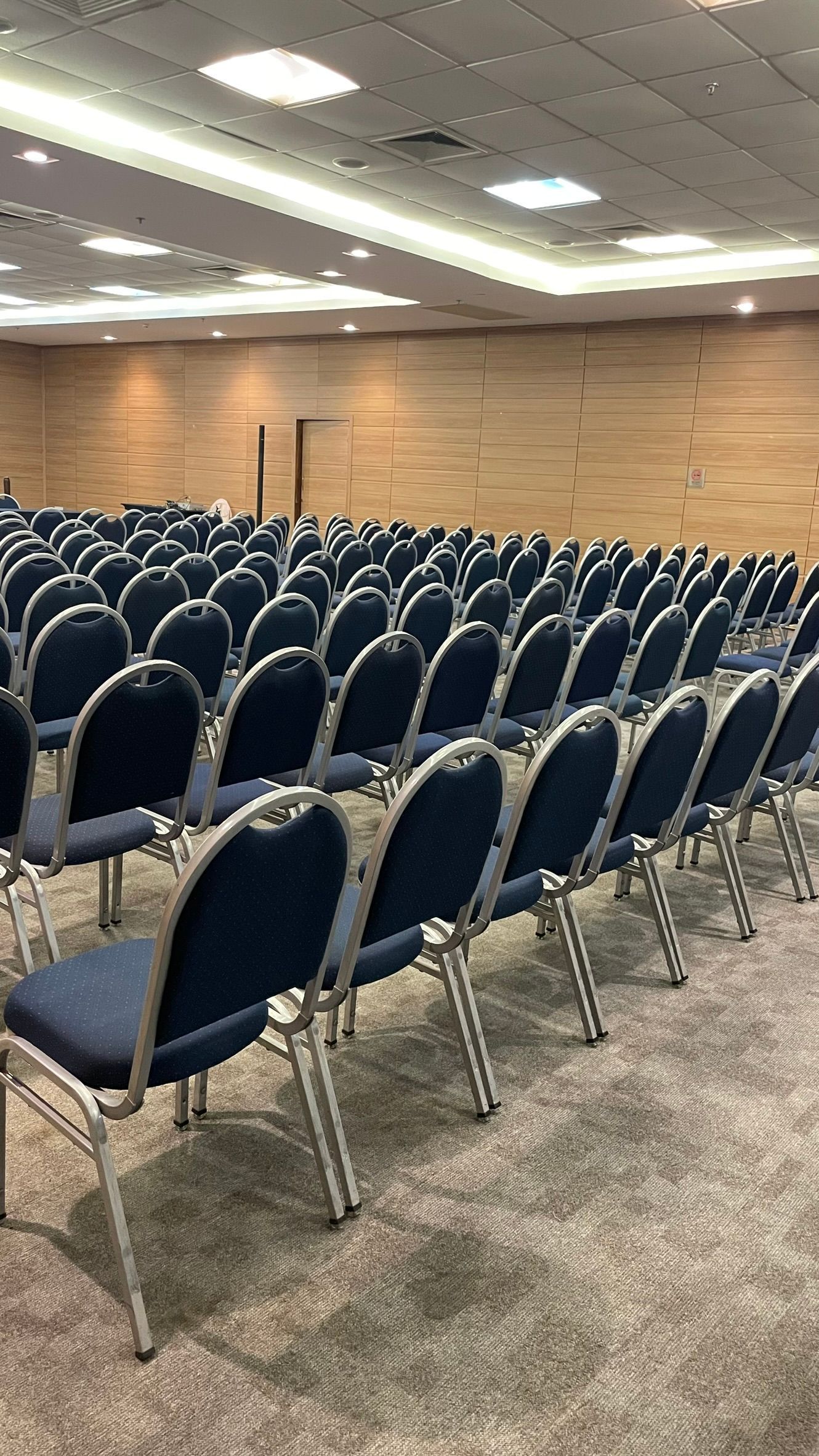 Uma grande sala de conferências cheia de fileiras de cadeiras azuis.