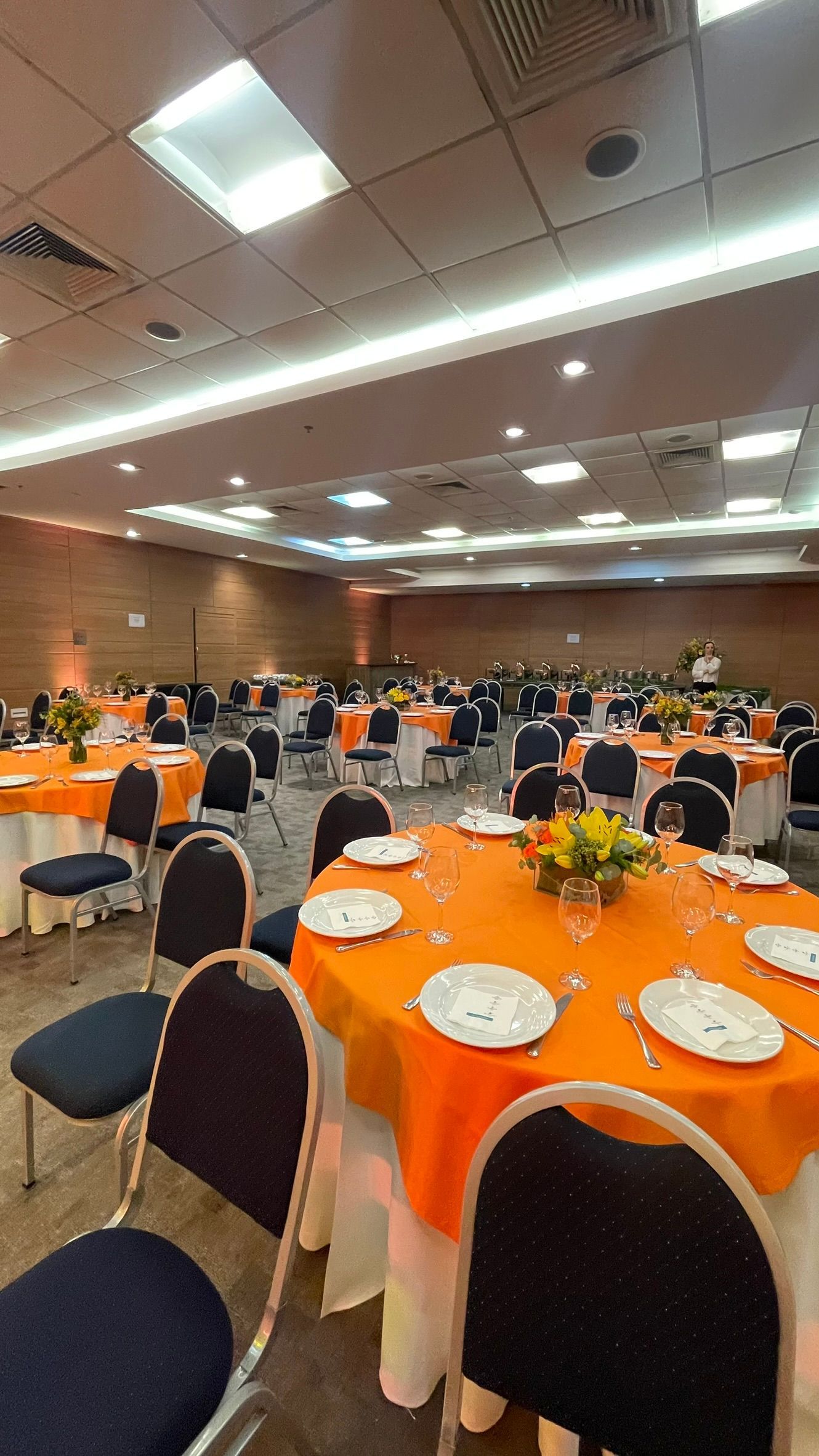 Uma sala grande com mesas e cadeiras preparadas para uma festa.