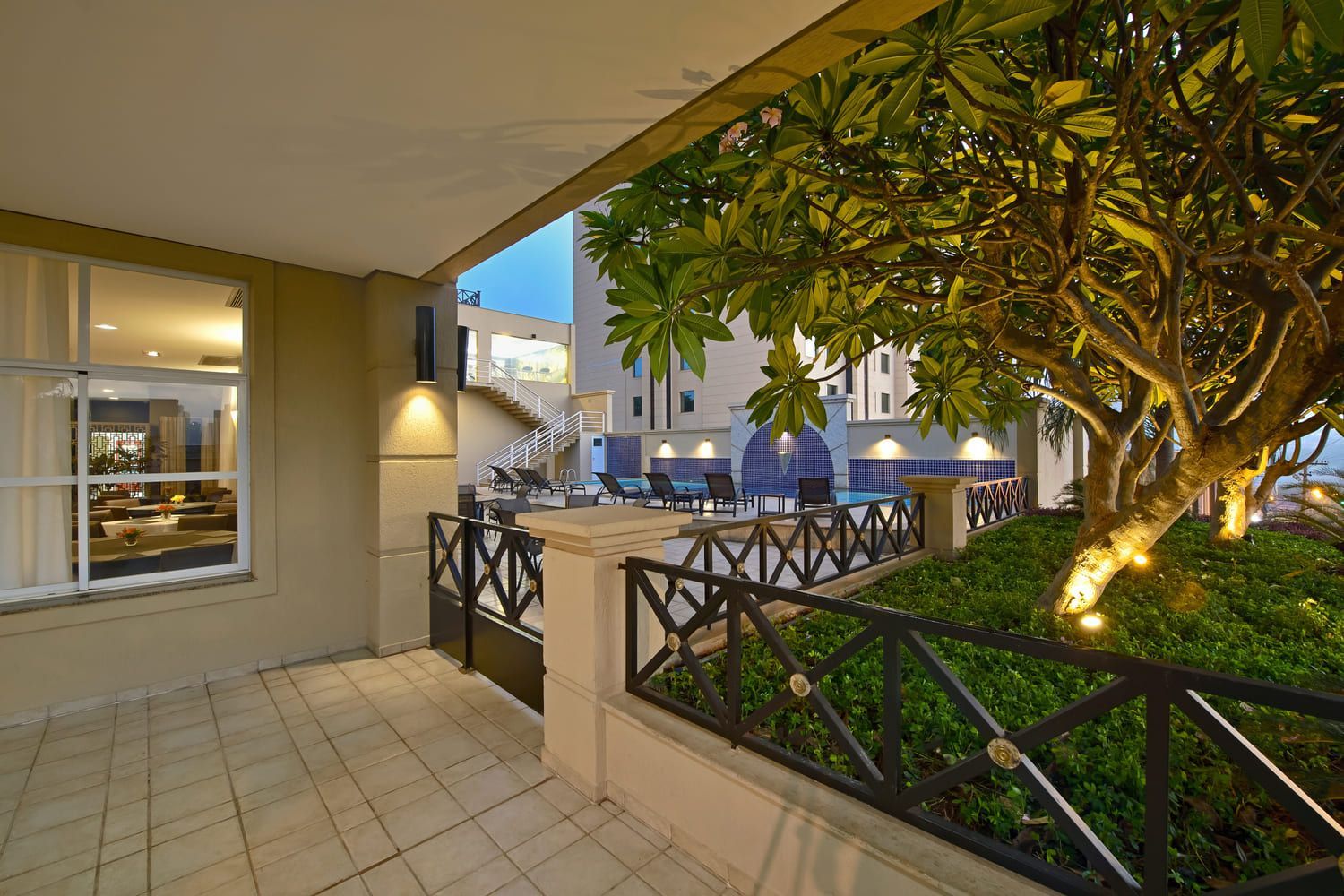 Um pátio com uma cerca e uma árvore em frente a um prédio.