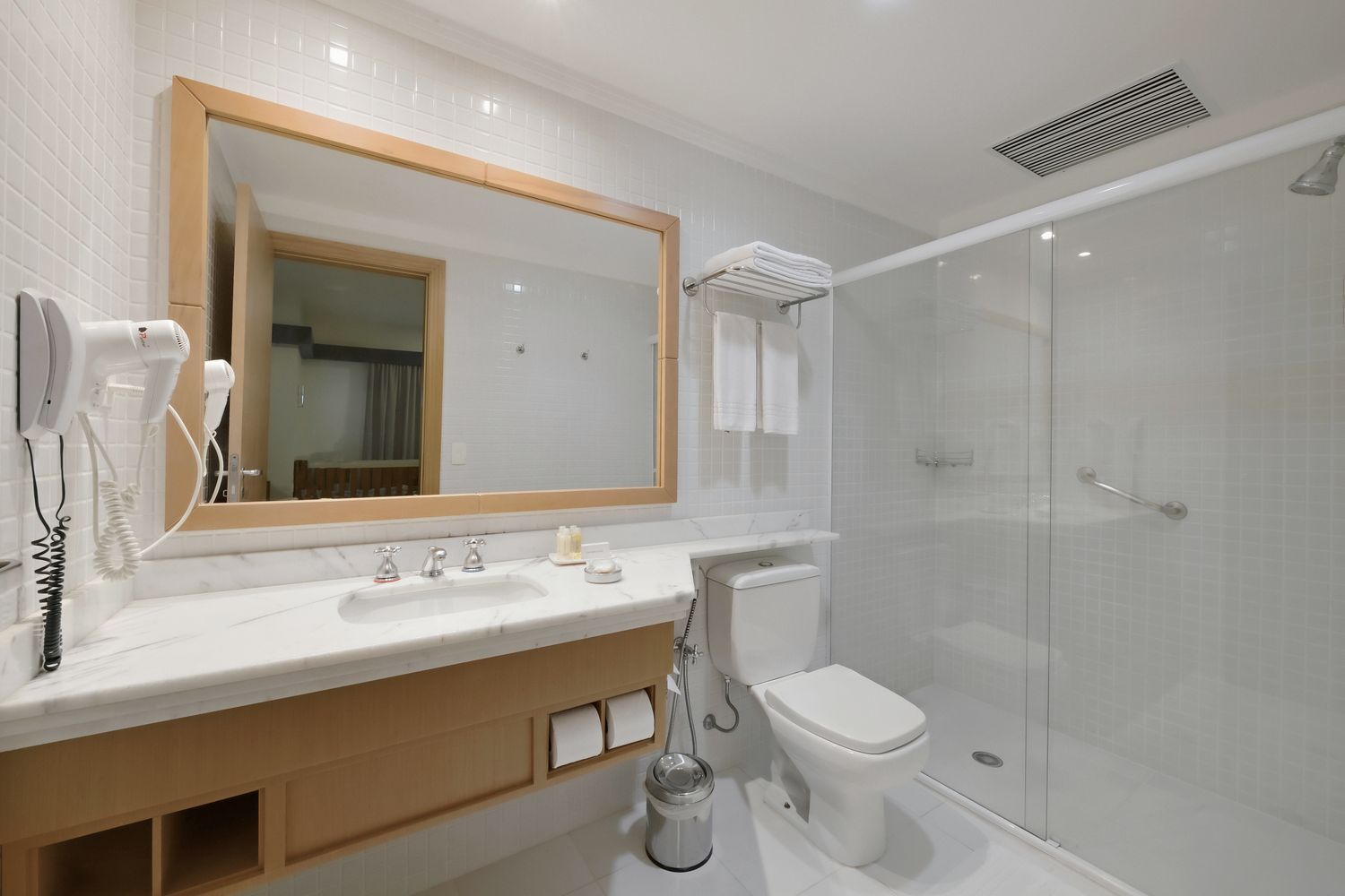 Um banheiro com vaso sanitário, pia, espelho e chuveiro.