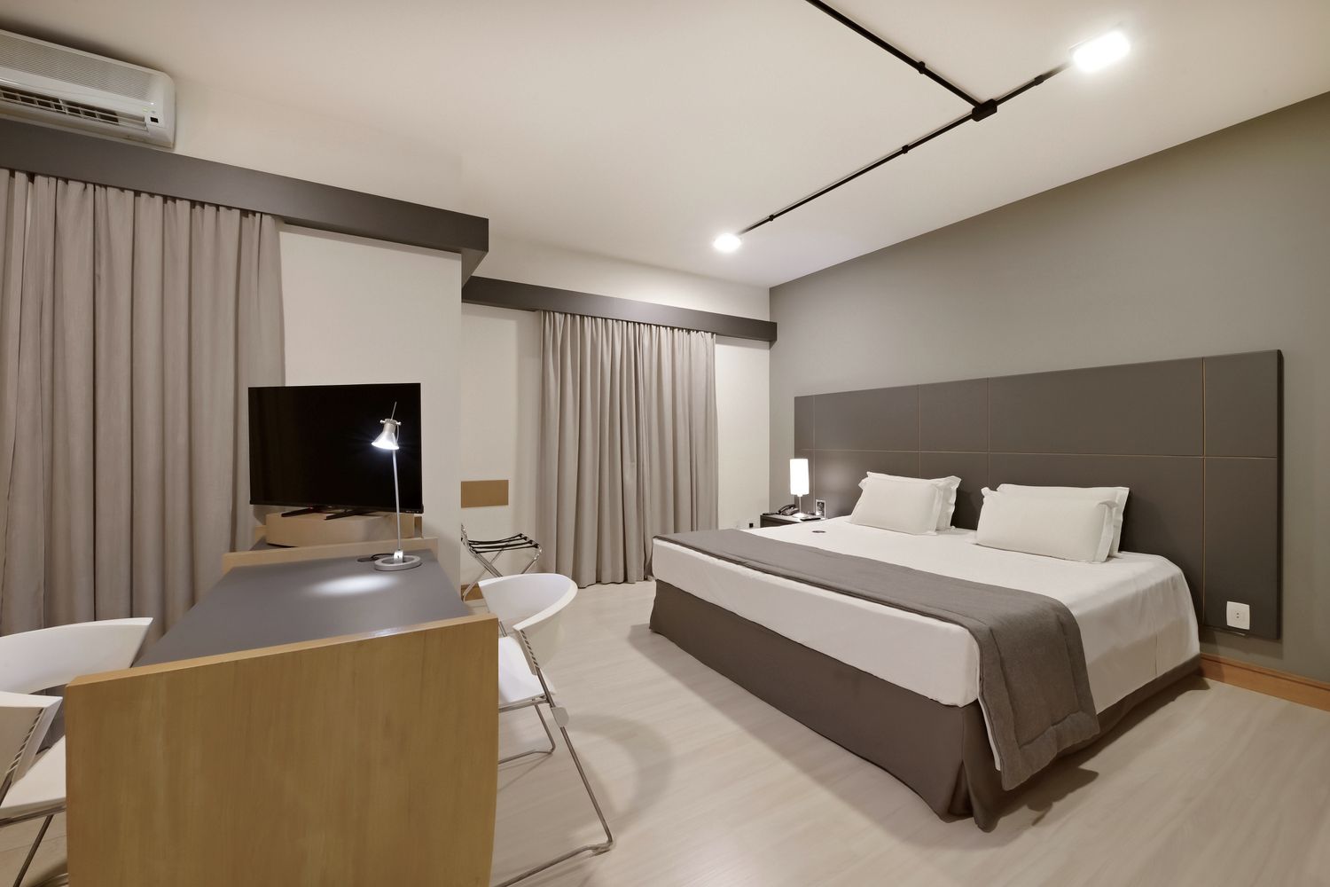 Um quarto de hotel com uma cama king size, escrivaninha e televisão.