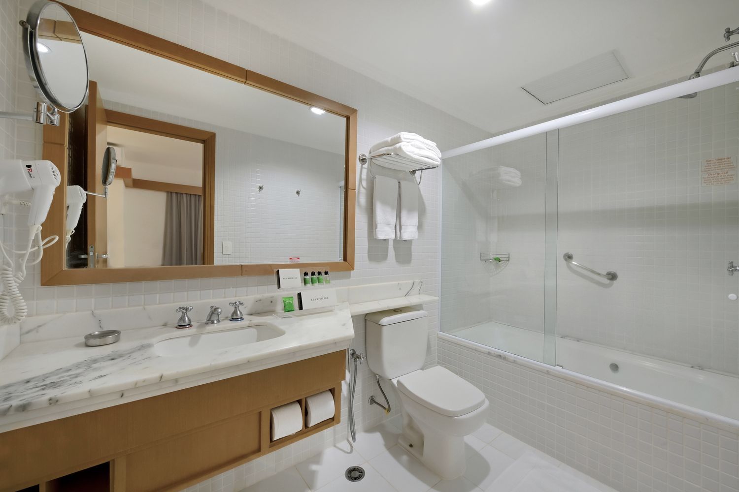 Um banheiro com vaso sanitário, pia, espelho e banheira.