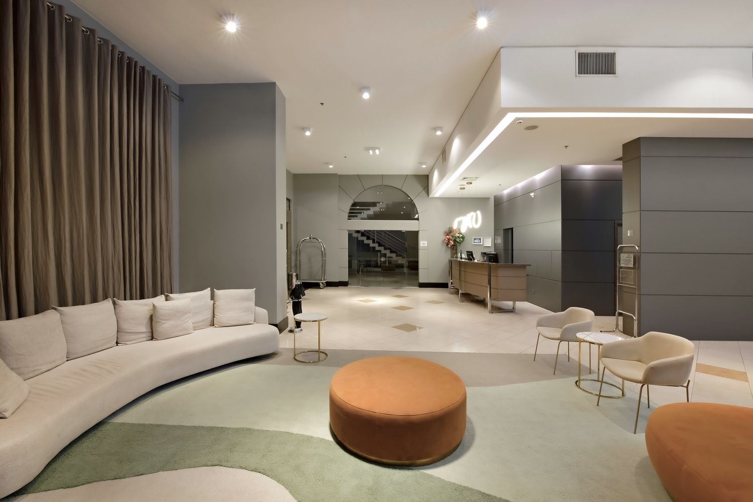 Uma sala de estar com um sofá, cadeiras e pufe.