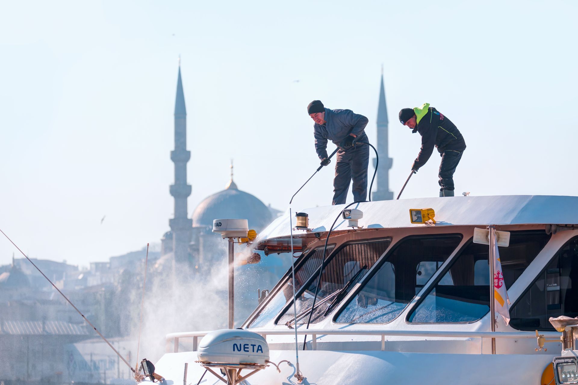 Two men are cleaning the roof of a boat.