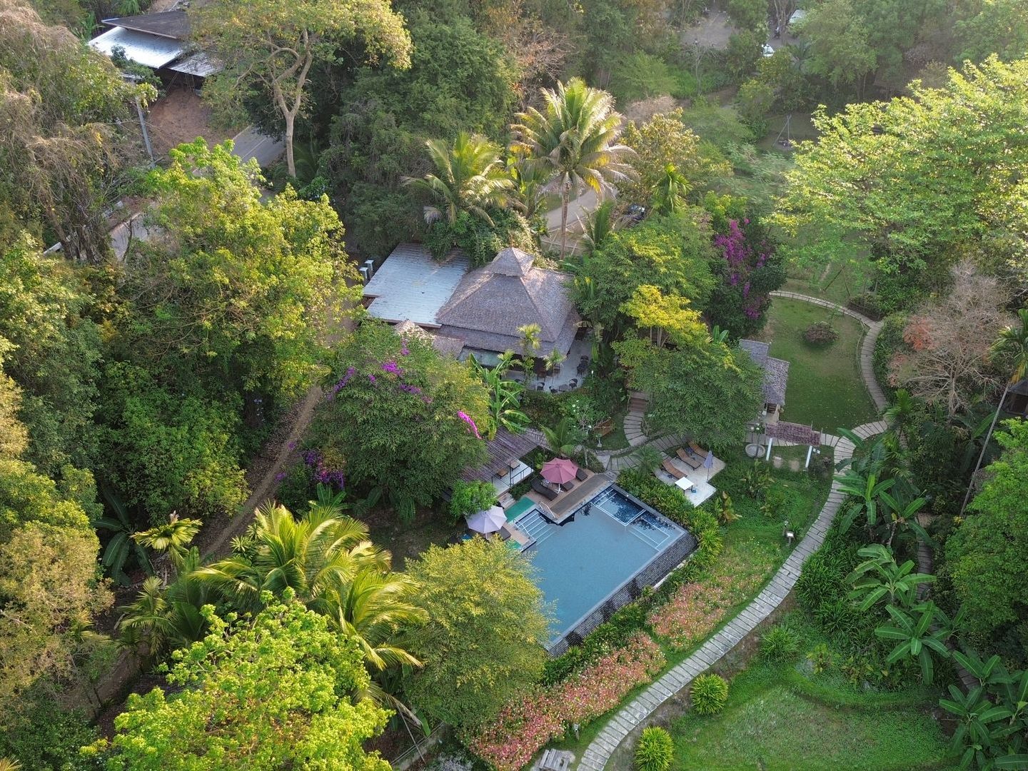 An aerial view of a house surrounded by trees and a swimming pool.
