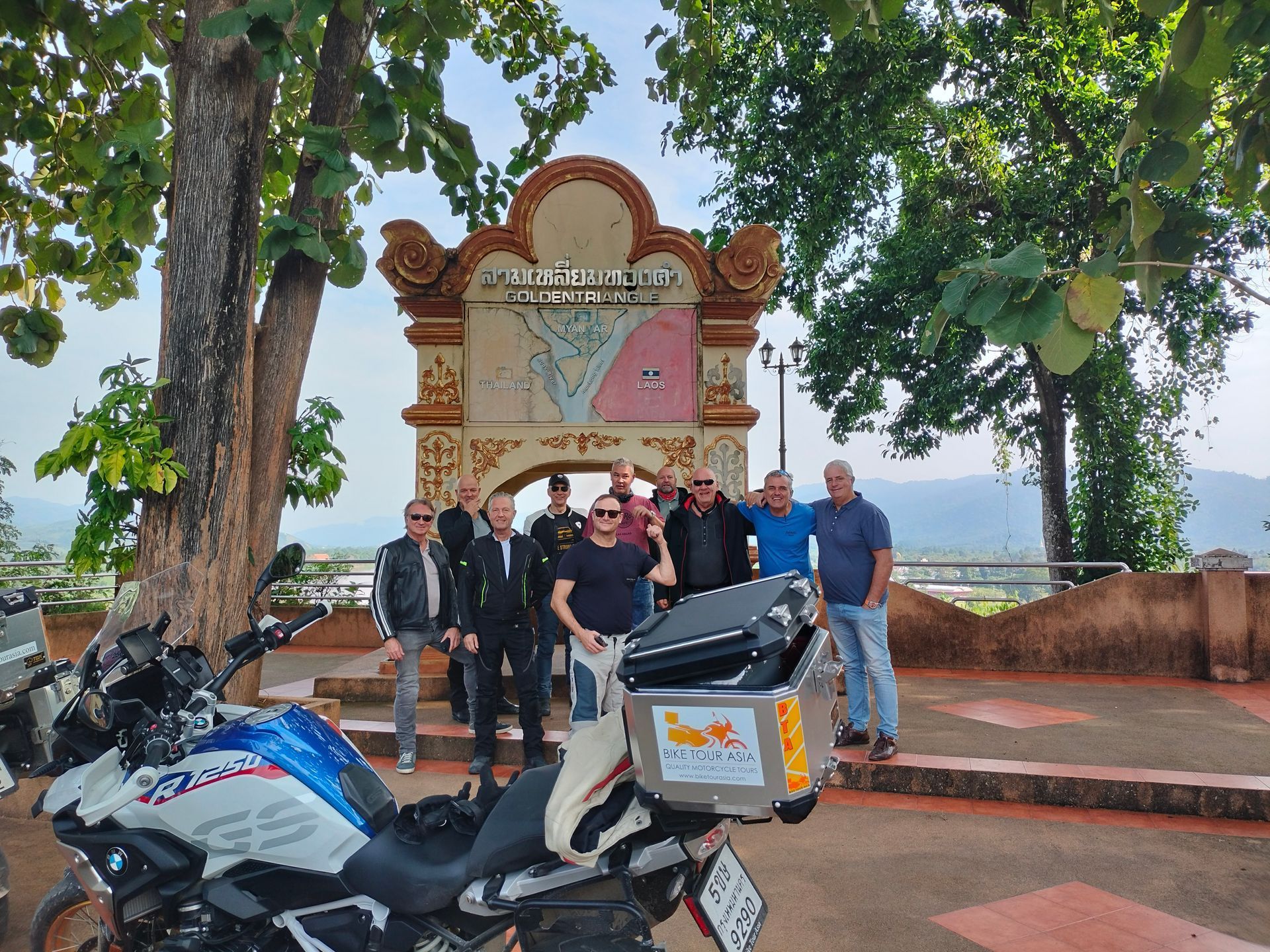 A group of men are posing for a picture next to motorcycles.