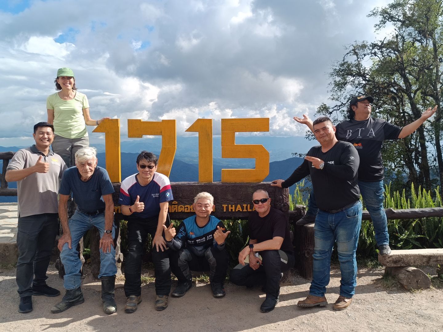 A group of people are posing for a picture in front of a sign that says 1715.