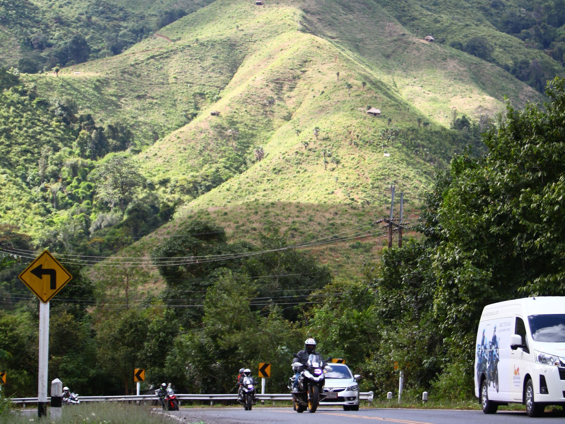 A bus is driving down a road with a mountain in the background in Nan