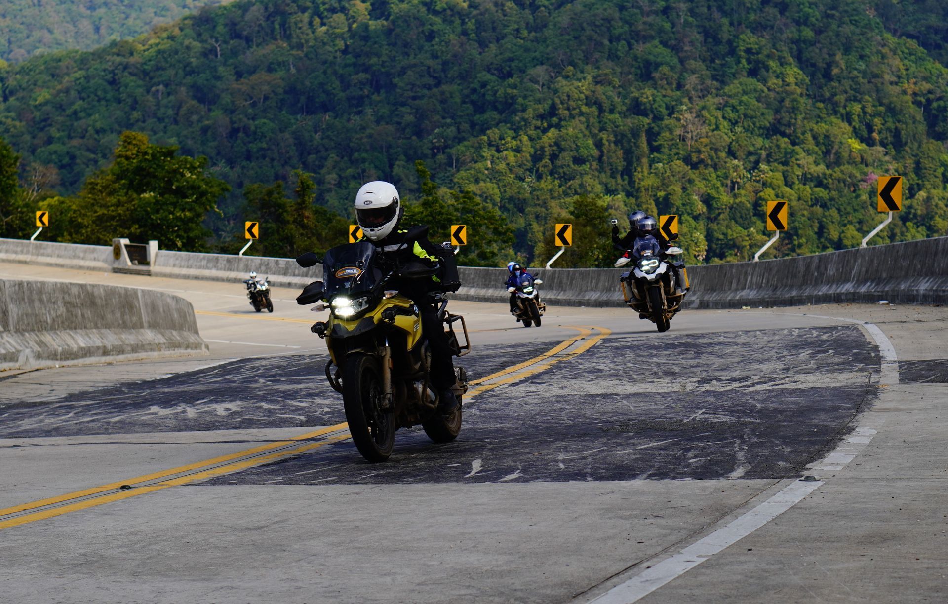 Group of motorcyclists riding through a sharp curve on the Mae Hong Son Loop in northern Thailand