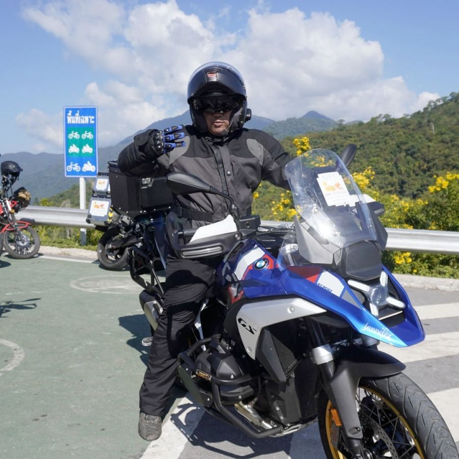 Adventure motorcycle rider stopping on a mountain road in Northern Thailand during a guided motorcycle tour