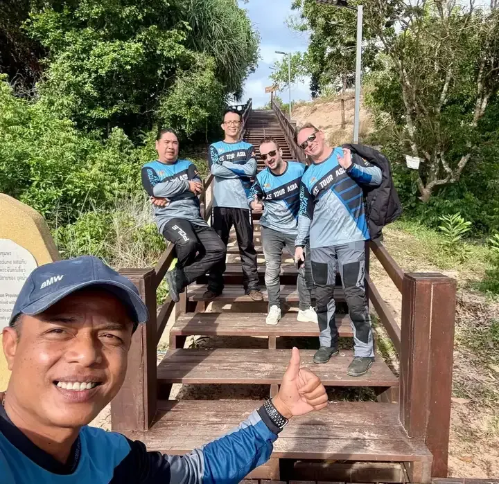 Bike Tour Asia riders posing on wooden stairs during a scenic stop on the Chiang Mai to Phuket motorcycle tour in Thailand