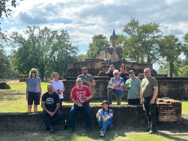Bike Tour Asia riders posing for a group photo at a historic Buddha temple ruin in Sukhothai, Thailand.