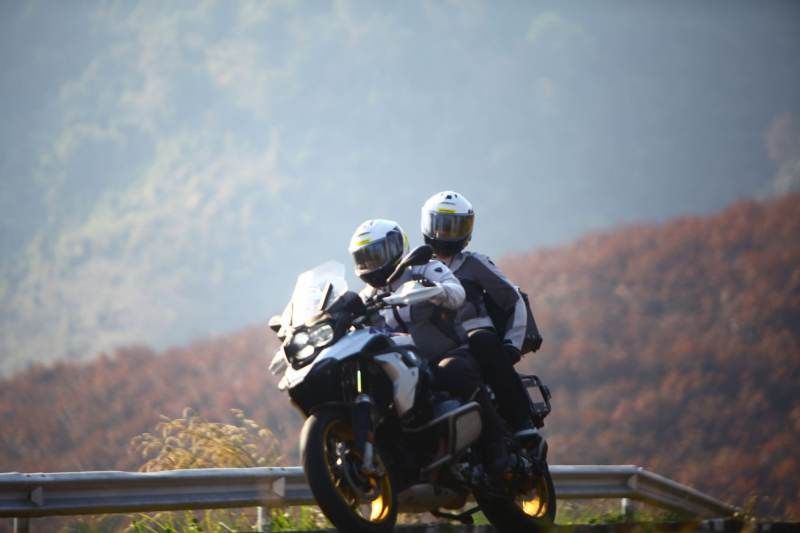 Two motorcycle riders in full gear riding through a mountain road in Thailand during a Bike Tour Asia tour.