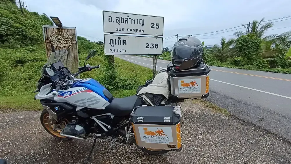 BMW R 1250 GS Adventure motorcycle parked by road sign showing distance to Phuket during Bike Tour Asia journey