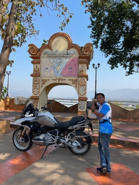 Rider with BMW motorcycle at the Golden Triangle landmark between Thailand Laos and Myanmar
