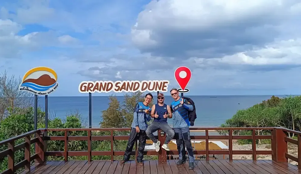 Motorcycle tour riders posing at Grand Sand Dune viewpoint overlooking the sea in Thailand