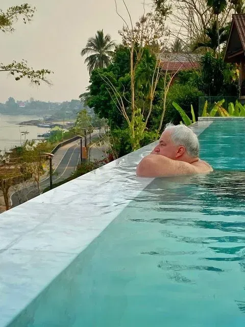 Traveler relaxing in an infinity pool overlooking the Mekong River in Laos