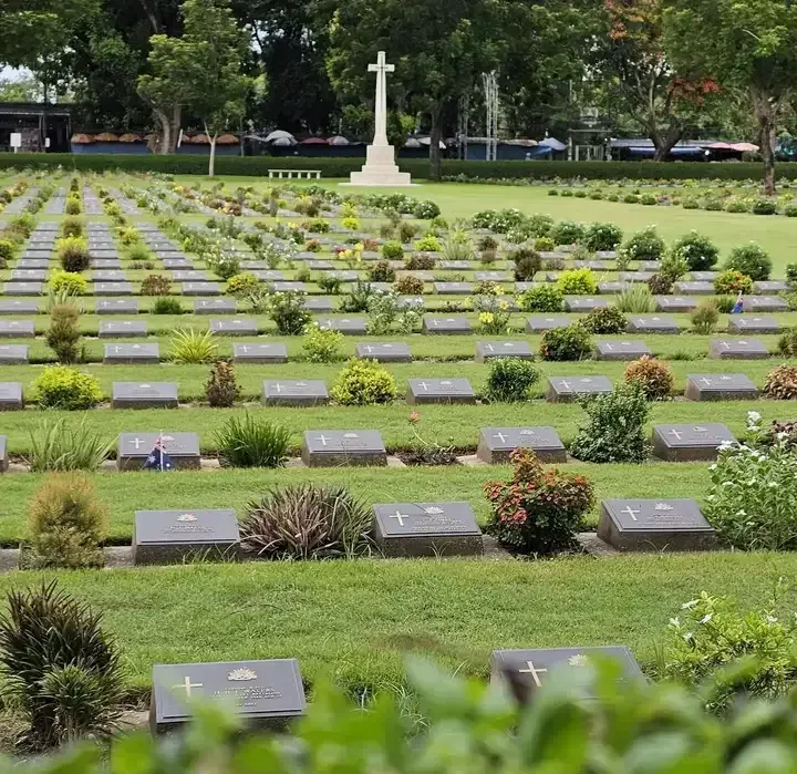 Kanchanaburi War Cemetery with aligned headstones and memorial cross honoring World War II soldiers in Thailand