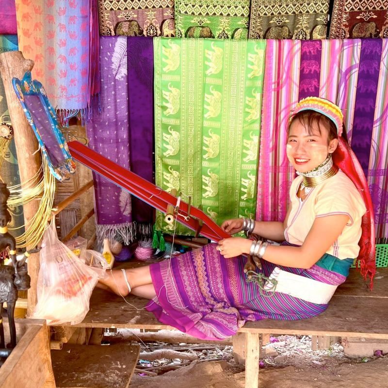 Kayan woman weaving traditional textiles on a handloom in a cultural village in Northern Thailand”