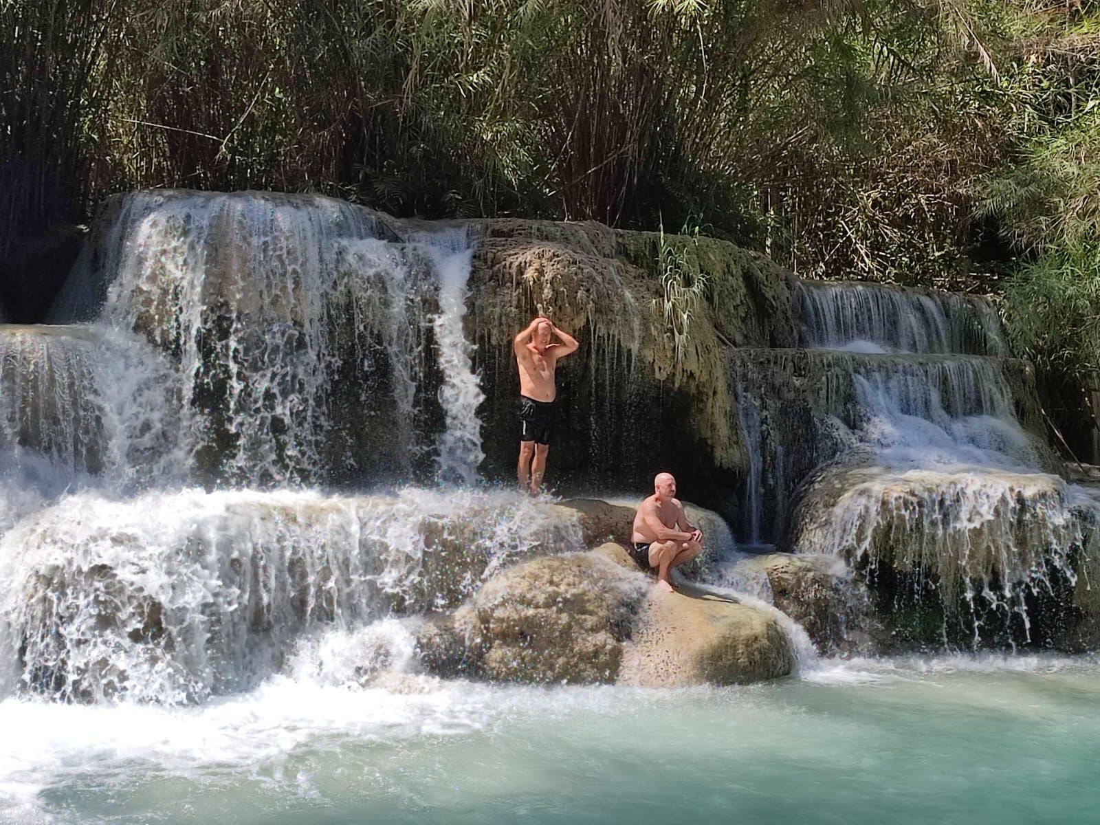Travelers swimming at the turquoise Kuang Si Waterfall in Luang Prabang Laos