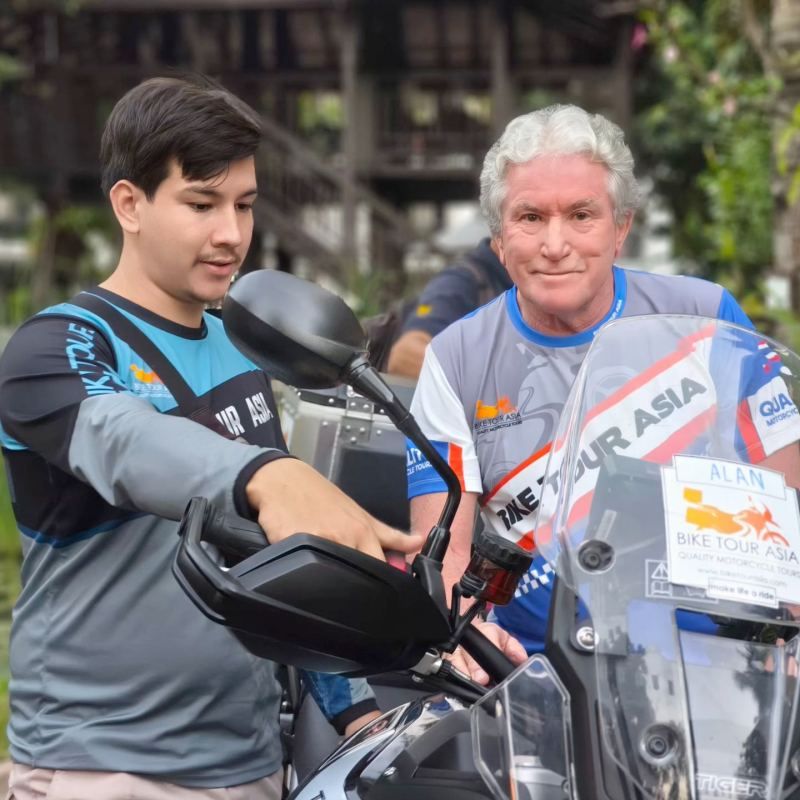 Bike Tour Asia guide assisting a rider during a motorcycle briefing before a guided tour