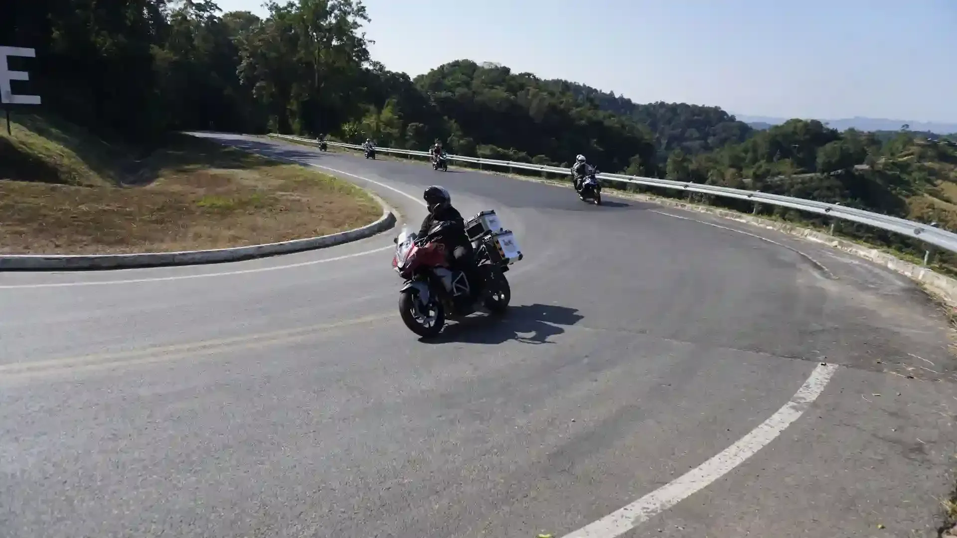 Group of motorcyclists riding through a sharp curve on the Mae Hong Son Loop in northern Thailand