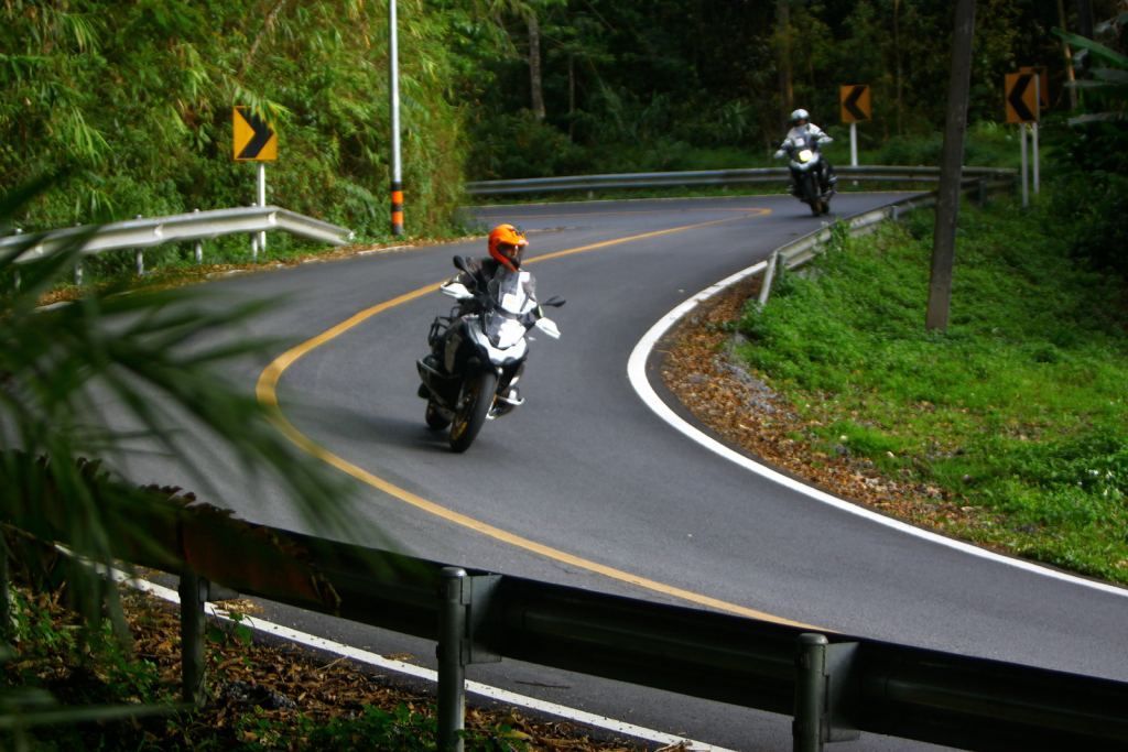 Adventure motorcycle riders navigating winding forest roads in Northern Thailand