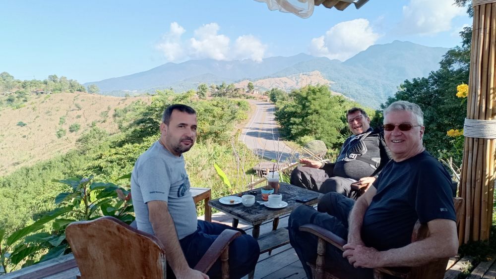 Motorcycle tour riders relaxing at a coffee stop with mountain views in Northern Thailand