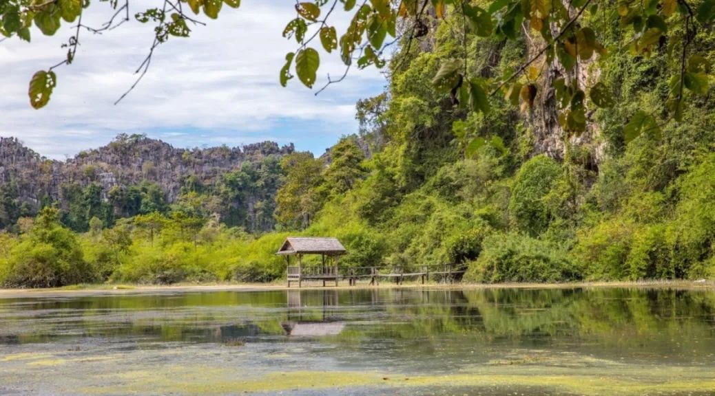 Serene lakeside lodge surrounded by limestone cliffs in Phou Hin Boun, Laos