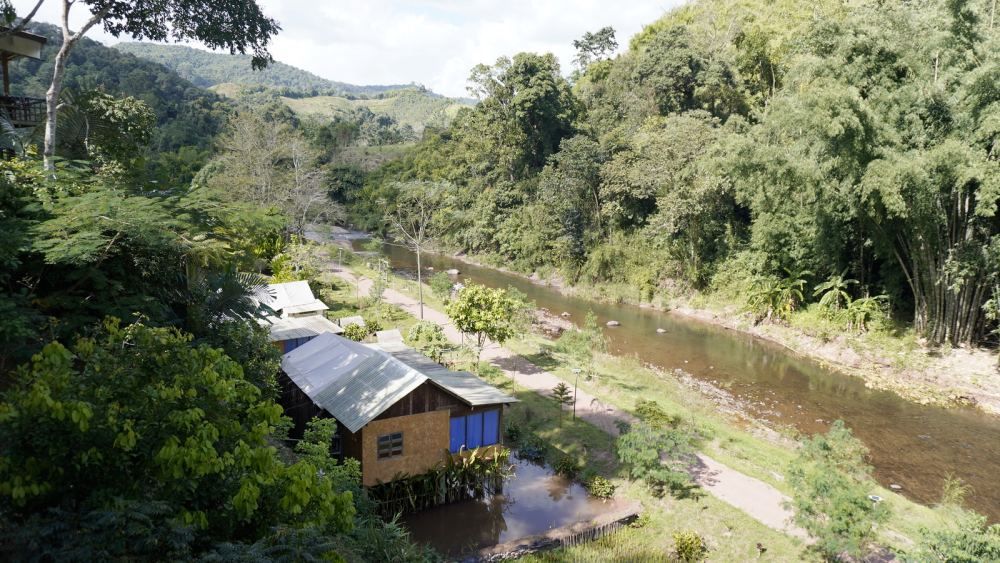 Riverside village surrounded by forested hills in rural Northern Thailand