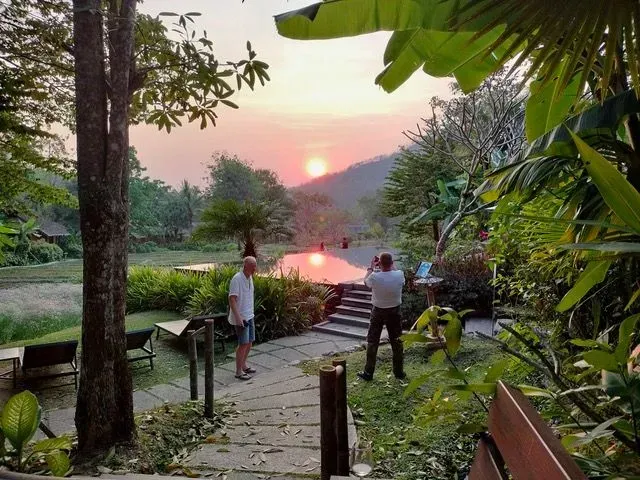 Guests watching sunset over lush hills at a peaceful resort in northern Thailand