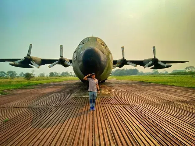 Traveler saluting in front of vintage war aircraft near Luang Prabang, Laos