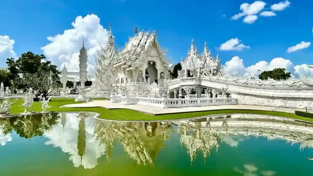 Stunning White Temple Wat Rong Khun in Chiang Rai reflected in the pond on a sunny day