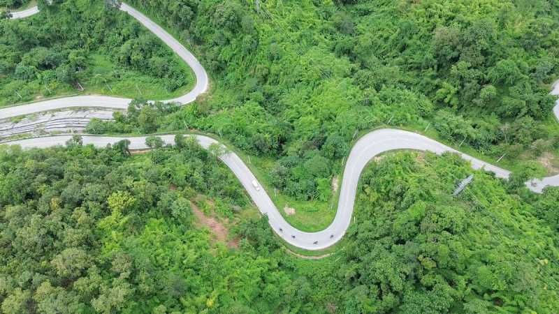 Aerial view of a winding mountain road through lush forest in Northern Thailand