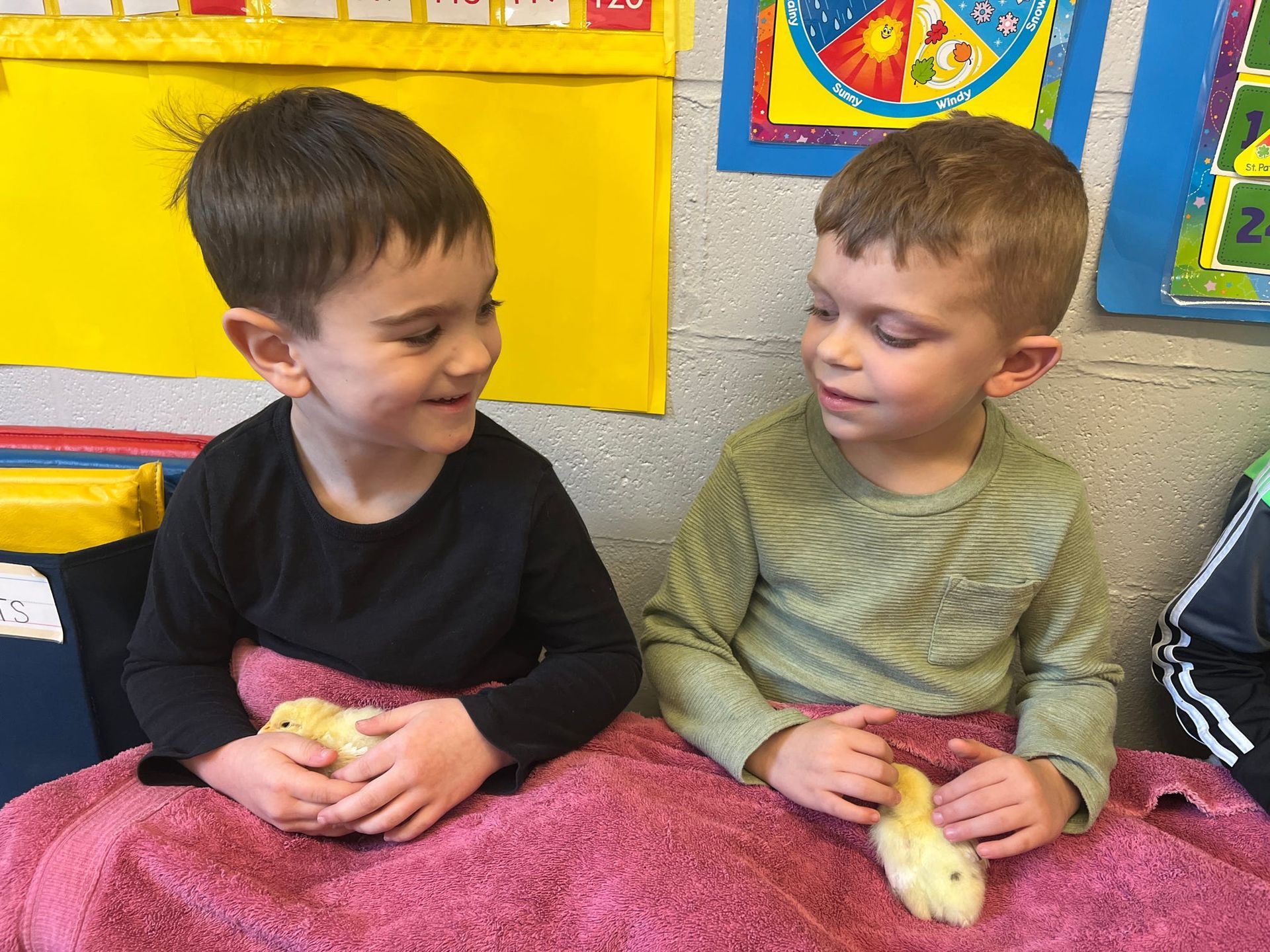 Two young boys are sitting next to each other holding a banana.