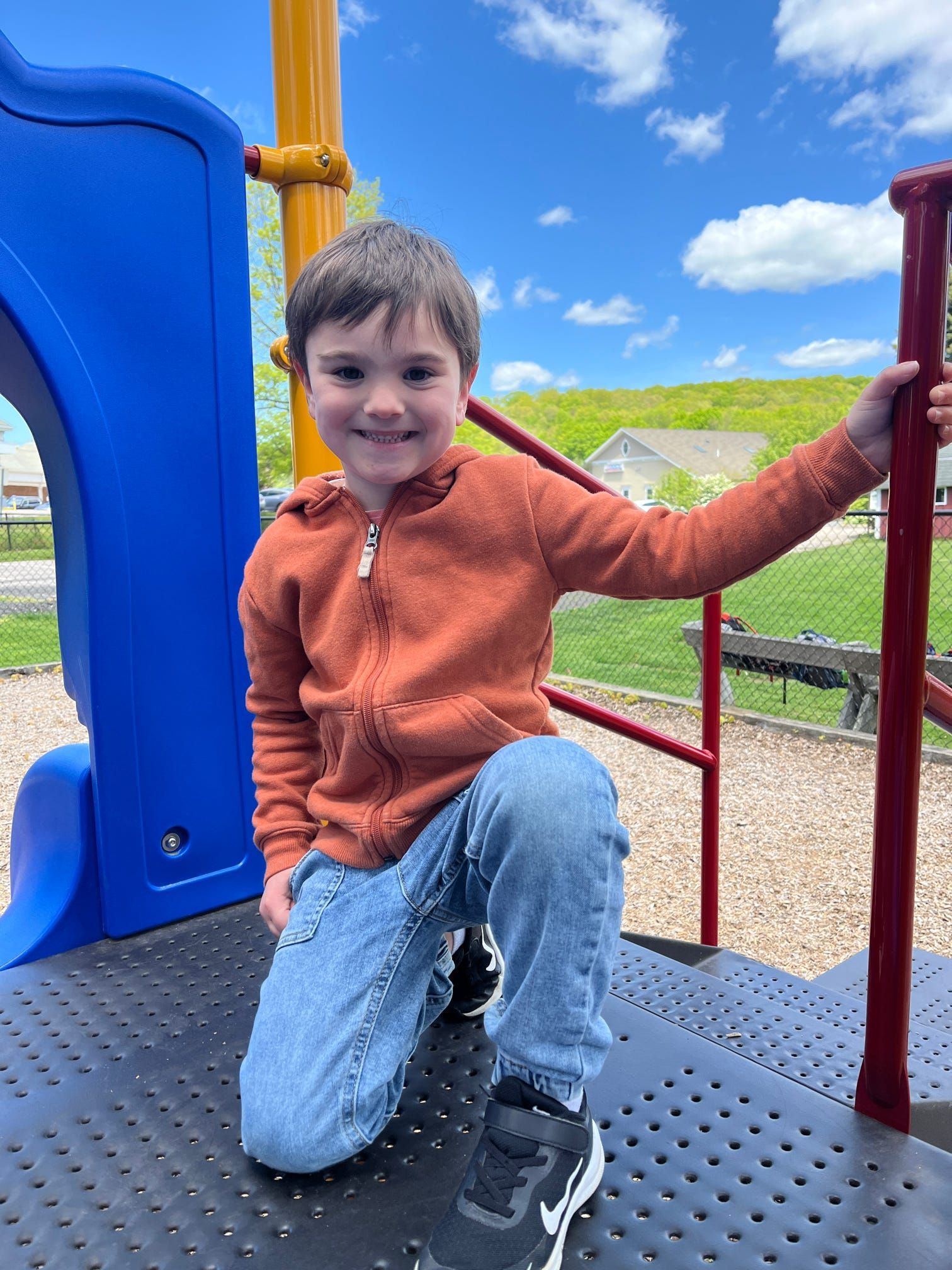 A young boy is sitting on a slide at a playground.