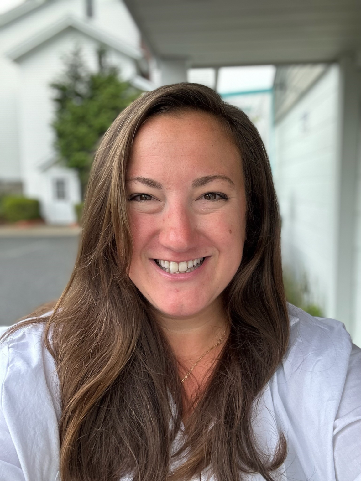 A woman with long brown hair is smiling for the camera.