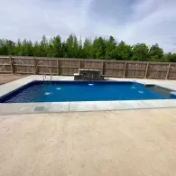 inground pool with sprinklers and waterfall